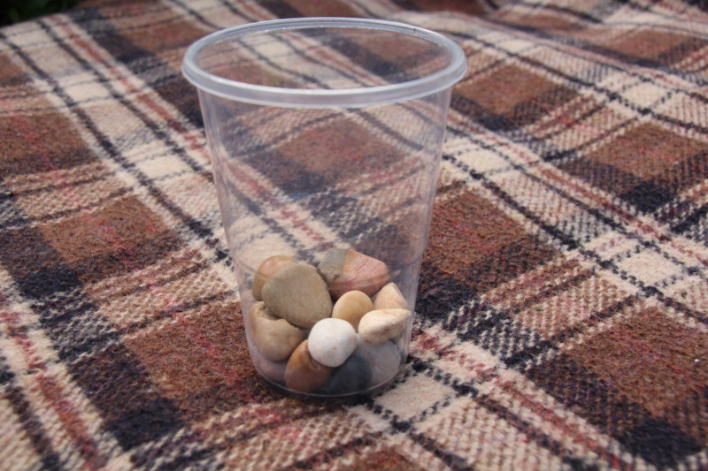 a see through pot containing a few small pebbles for a counting game